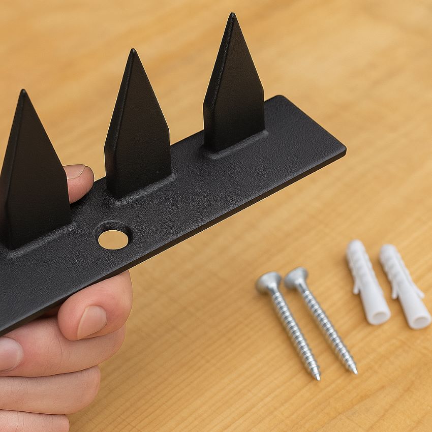 Hand holding a powder‑coated steel spike strip with pre‑drilled holes, showing screws and plugs ready for installation