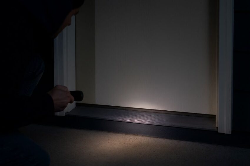 Nighttime flashlight test showing light leakage at the door bottom before installing a sweep