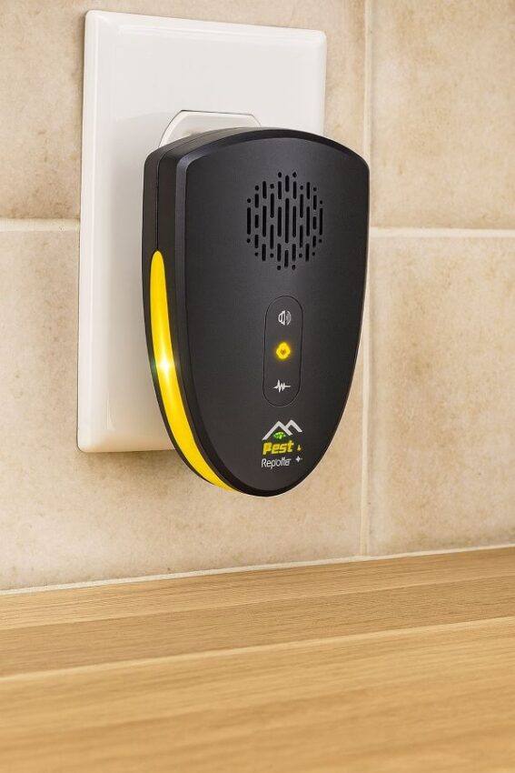 Plug-in indoor ultrasonic rodent repeller in a kitchen outlet with status light on.