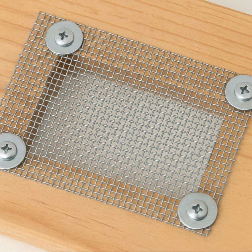 Stainless mesh secured over a wooden vent opening using stainless screws and fender washers