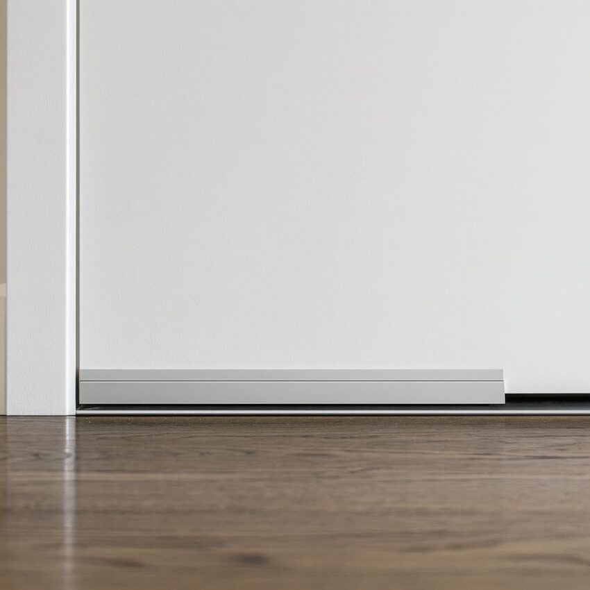 Surface-mounted 2-strip aluminum automatic door bottom sealing the gap at the threshold.