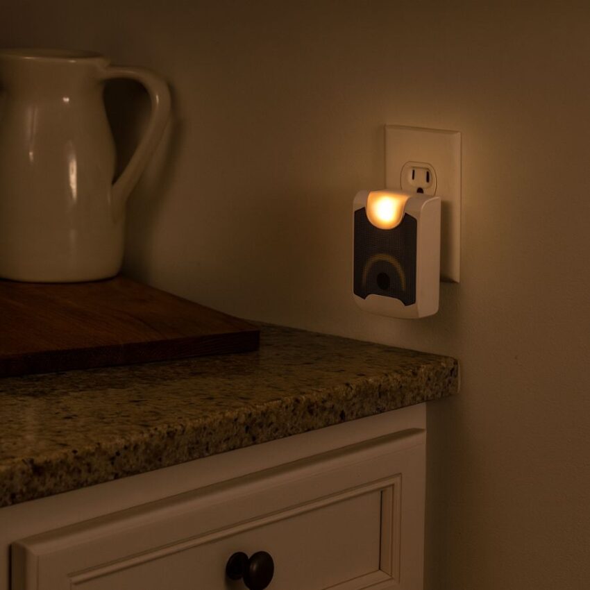 Ultrasonic pest repeller plugged into a kitchen outlet with night light on, showing non-chemical use in a family space.