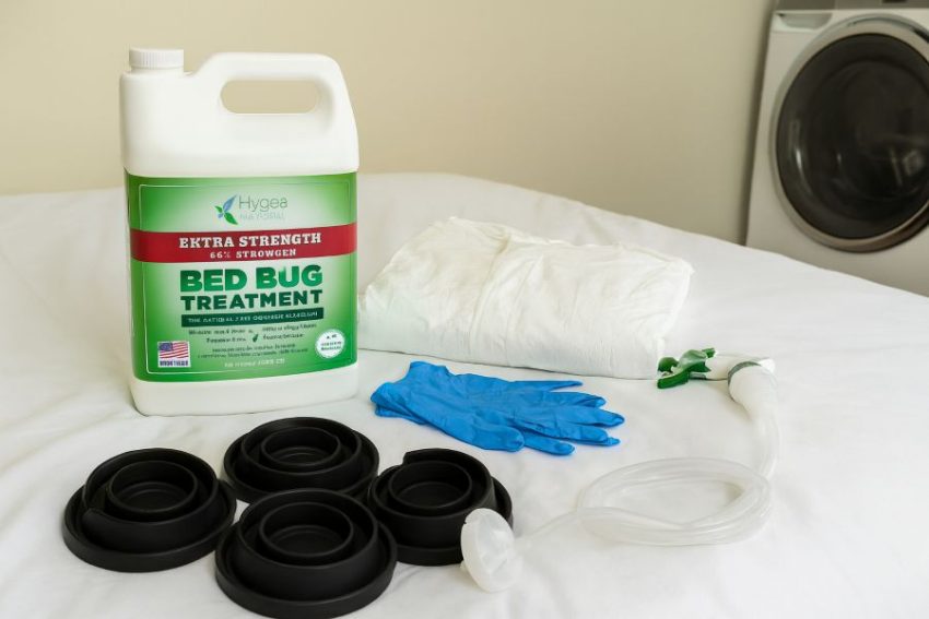 Natural bed bug treatment spray with XL coveralls and interceptors beside a clean bed and dryer, ready for an IPM session