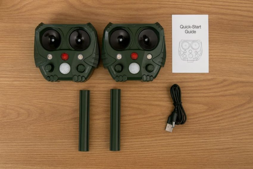Two solar animal repellers with stakes and USB cable arranged for a quick start guide photo